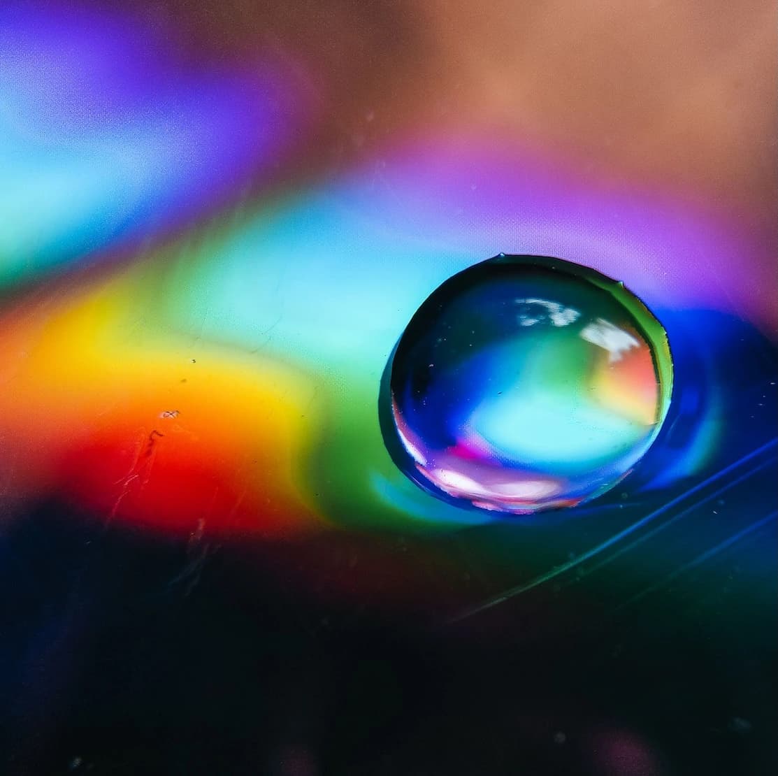 Close-up of a water droplet showcasing vibrant rainbow refraction.