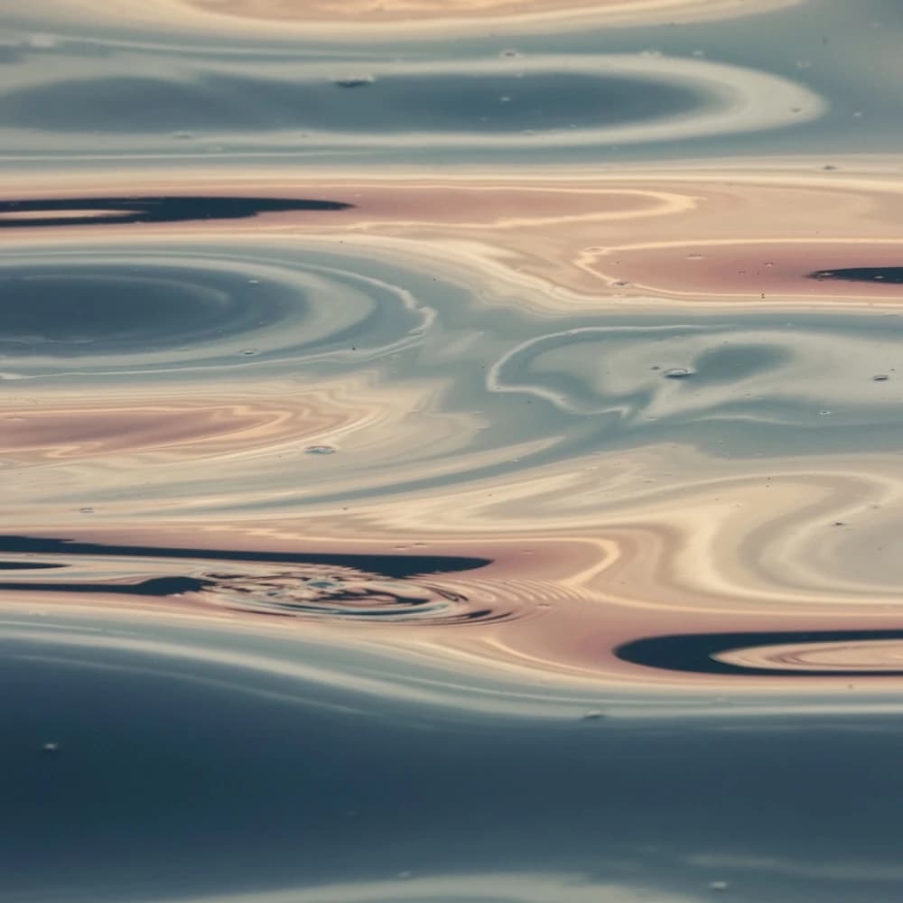 Beautiful abstract reflections on water surface with serene swirls and soft sunset colors.